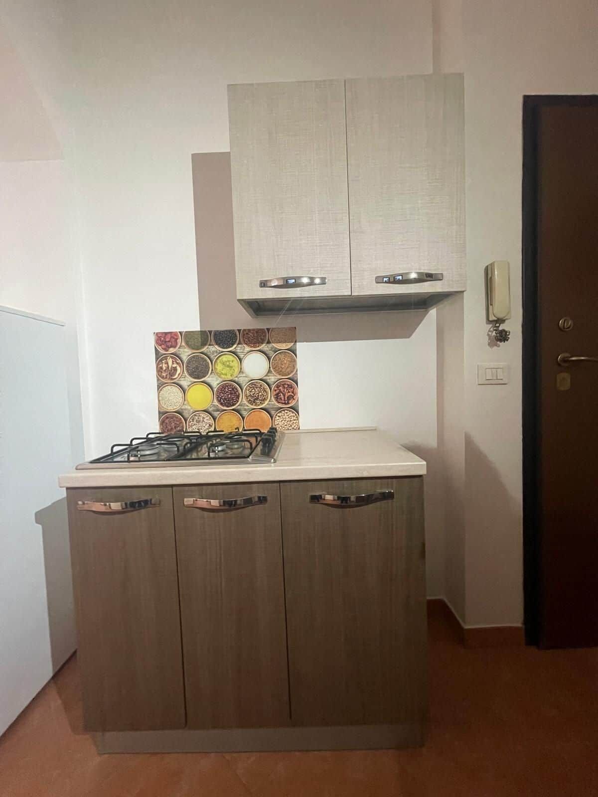 Une cuisine de taille réduite, dotée d’une cuisinière à gaz, de meubles en bois et d’un crédence décorée.