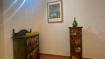 Une pièce dotée d’un sol carrelé, d’un climatiseur fixé au mur, d’une œuvre d’art encadrée et d’un meuble décoratif.