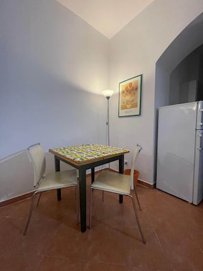 Ein Essbereich mit Tisch und Stühlen, einem Kühlschrank und einer Stehlampe.