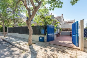 A gated residential area with a paved walkway, trees, and a building with a white facade. - Hola House Mondello Addaura (Palermo)