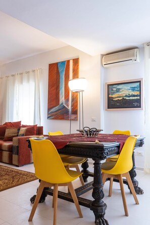 A dining area with a round table, yellow chairs, and a modern lamp. - Hola House Politeama Theater (Palermo)