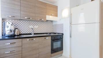Une cuisine moderne avec des meubles en bois, une cuisinière à gaz, un four encastré et un réfrigérateur blanc.