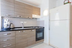 Eine moderne Küche mit Holzausstattung, einem Gasherd, einem Backofen und einem weißen Kühlschrank.