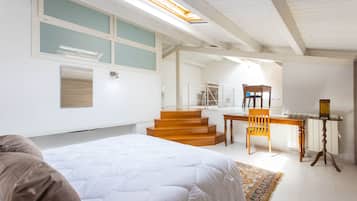 Une chambre à coucher avec un lit, un bureau et une chaise. Un escalier mène à un étage supérieur.