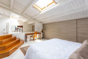 Ein Schlafzimmer mit Bett, einer Holztreppe, einem Schreibtisch und einem Stuhl.