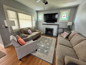 A living room with a fireplace, a television, and two sofas. - Walkable Top of Queen Anne 5BR + Parking (Seattle)