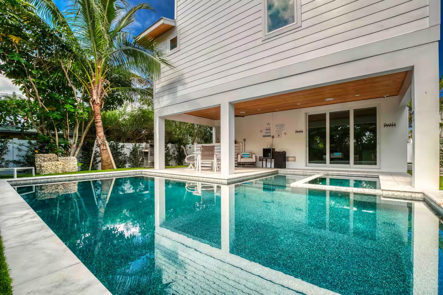 A modern house with a swimming pool, outdoor seating, and a covered patio area.