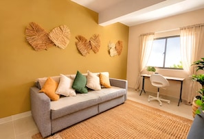 A modern living room with a grey sofa, a woven rug, and wall art. - Family Villa in Punta Cana | Private Pool, BBQ, and Kids' Area (Punta Cana)