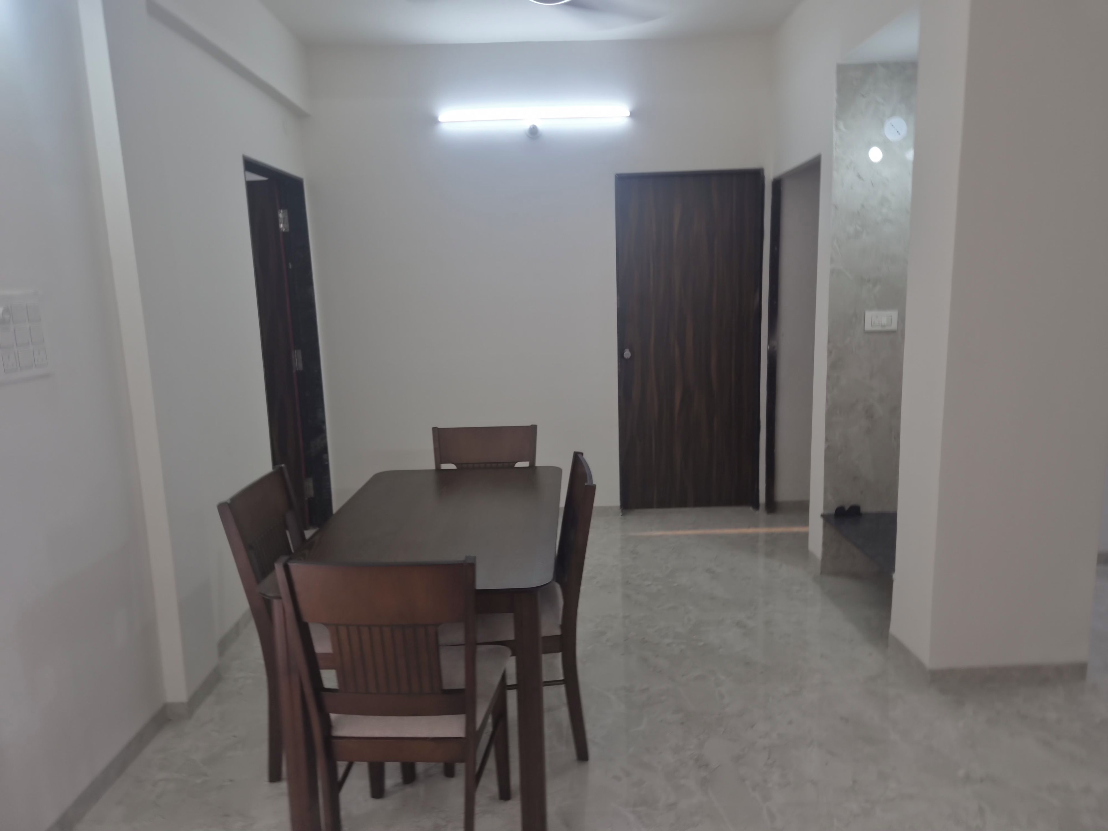 Un coin repas comprenant une table rectangulaire et six chaises, une porte en bois et un luminaire au plafond.
