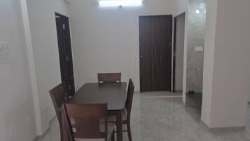 Un coin repas comprenant une table rectangulaire et six chaises, une porte en bois et un luminaire au plafond.