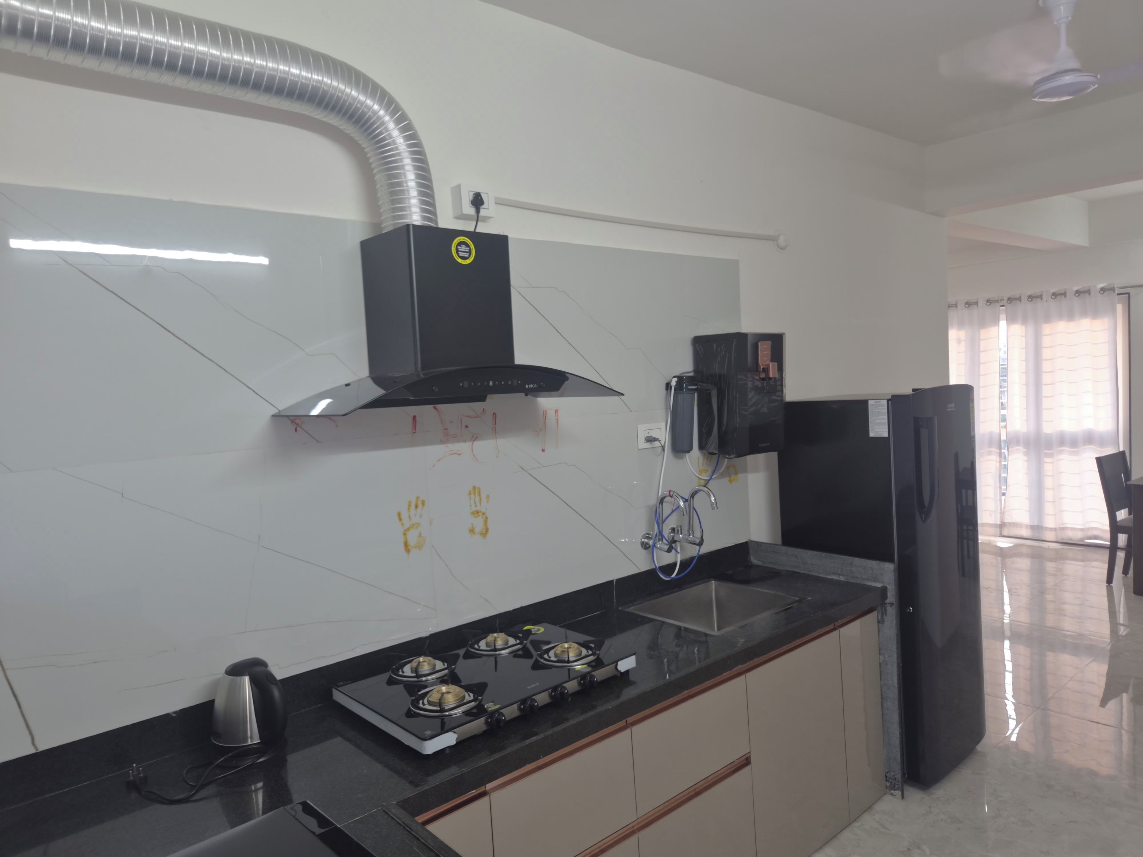 A modern kitchen with a gas stove, black cabinets, and a stainless steel range hood.