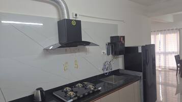 A modern kitchen with a gas stove, black cabinets, and a stainless steel range hood.