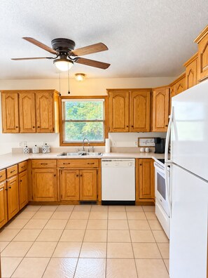 A kitchen with wooden cabinets, a dishwasher, a refrigerator, and a ceiling fan.