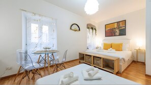 A modern hotel room with a bed, bedside table, and a dining area with chairs and a glass table. - Apartment 'Comfty  Piazza Navona' with Wi-Fi and Air Conditioning (Roma)