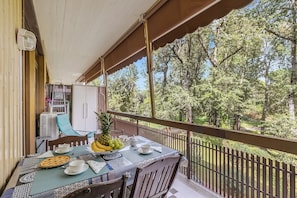 A balcony with a table set for dining, a chair, and a view of trees. - Park Apt With AC & Private Balcony, 300 mt to Sea (Viareggio)
