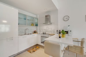 A modern kitchen with white cabinets, a stainless steel range hood, a built-in oven, and a microwave. - Park Apt With AC & Private Balcony, 300 mt to Sea (Viareggio)
