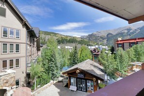 A mountain town with a view of a mountain range, a wooden building with a sign, and a multi-story building with windows. - Lake and Mountain Views. Center Village Gem. In unit washer and dryer! Steps fro (Copper Mountain)