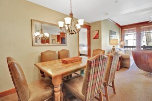 A dining area with a wooden table and chairs, a chandelier, and a large mirror on the wall. - Lake and Mountain Views. Center Village Gem. In unit washer and dryer! Steps fro (Copper Mountain)