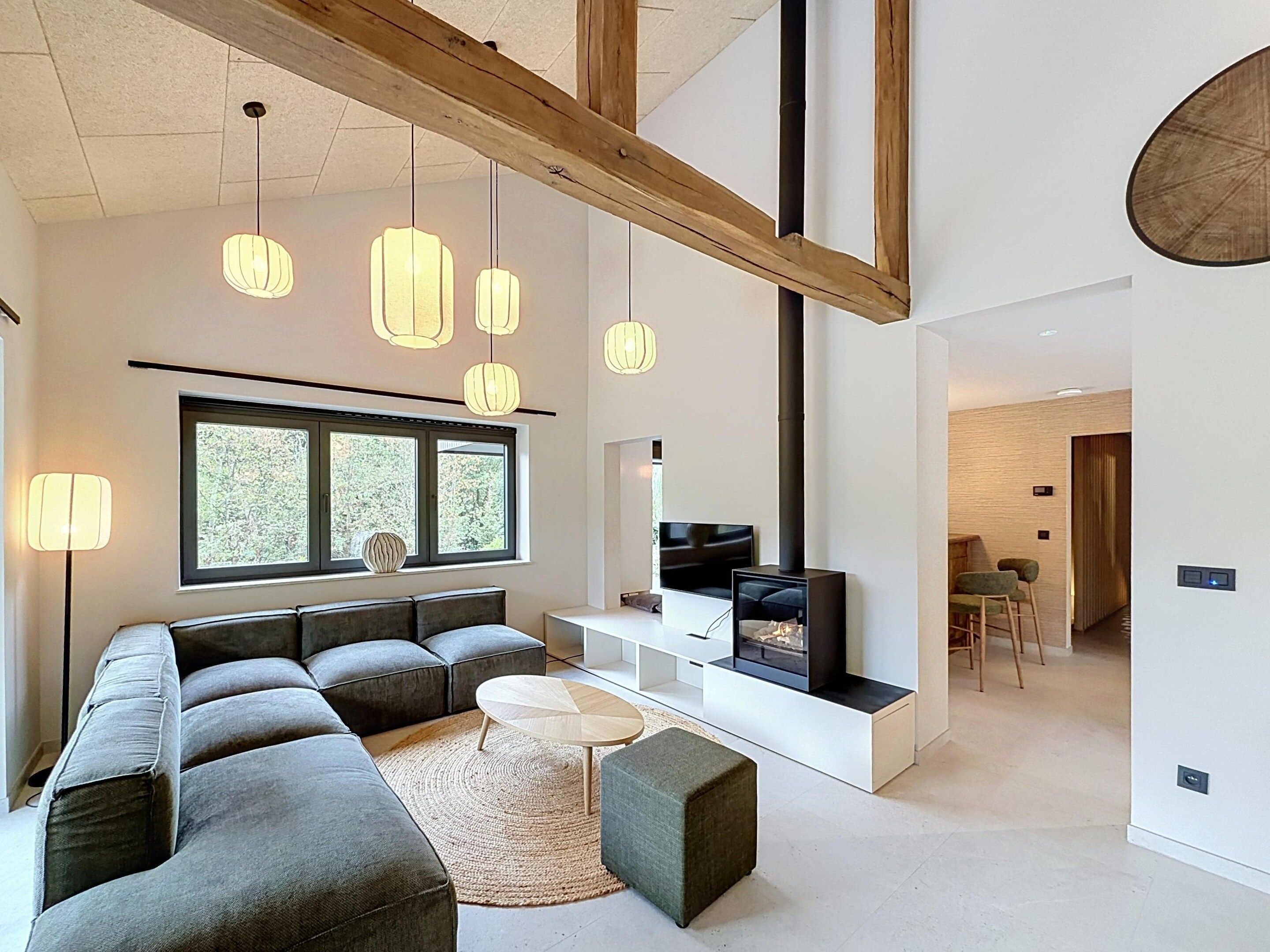Un salon moderne avec un canapé d’angle, un téléviseur et une cheminée.