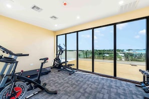 A gym with cardio equipment, large windows, and a view of the outdoors. - The Sands #5 (Seven Mile Beach)