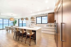 A modern kitchen with a large island, bar stools, and a view of the ocean. - The Sands #5 (Seven Mile Beach)