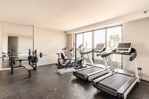 A gym with treadmills, an elliptical, and a squat rack. - EK SkySuite Altura Upperhill Floor 21 with Panoramic views (Nairobi)