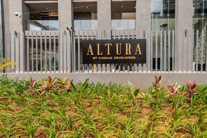 Une enseigne indiquant « ALTURA par CANAAAN DEVELOPERS », avec un bâtiment moderne en arrière-plan.