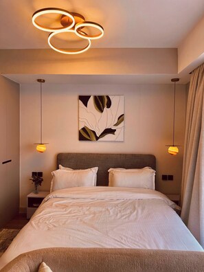A modern hotel room with a large bed, a headboard, a wall-mounted artwork, and a ceiling light fixture. - EK SkySuite Altura Upperhill Floor 21 with Panoramic views (Nairobi)