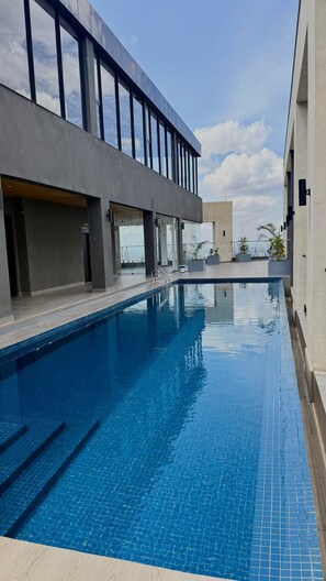 A modern building with a swimming pool, large windows, and a view of the city. - EK SkySuite Altura Upperhill Floor 21 with Panoramic views (Nairobi)
