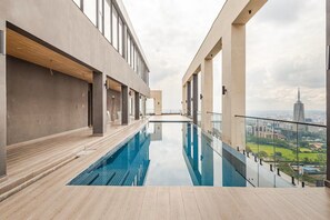 A modern indoor swimming pool with a city view, featuring a minimalist design and a clear glass barrier. - EK SkySuite Altura Upperhill Floor 21 with Panoramic views (Nairobi)