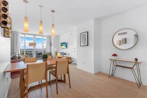 A modern kitchen with a dining area, large windows, and a view of the city. - Generous Space 2BR Condo - Intracoastal Marina (Hallandale Beach)