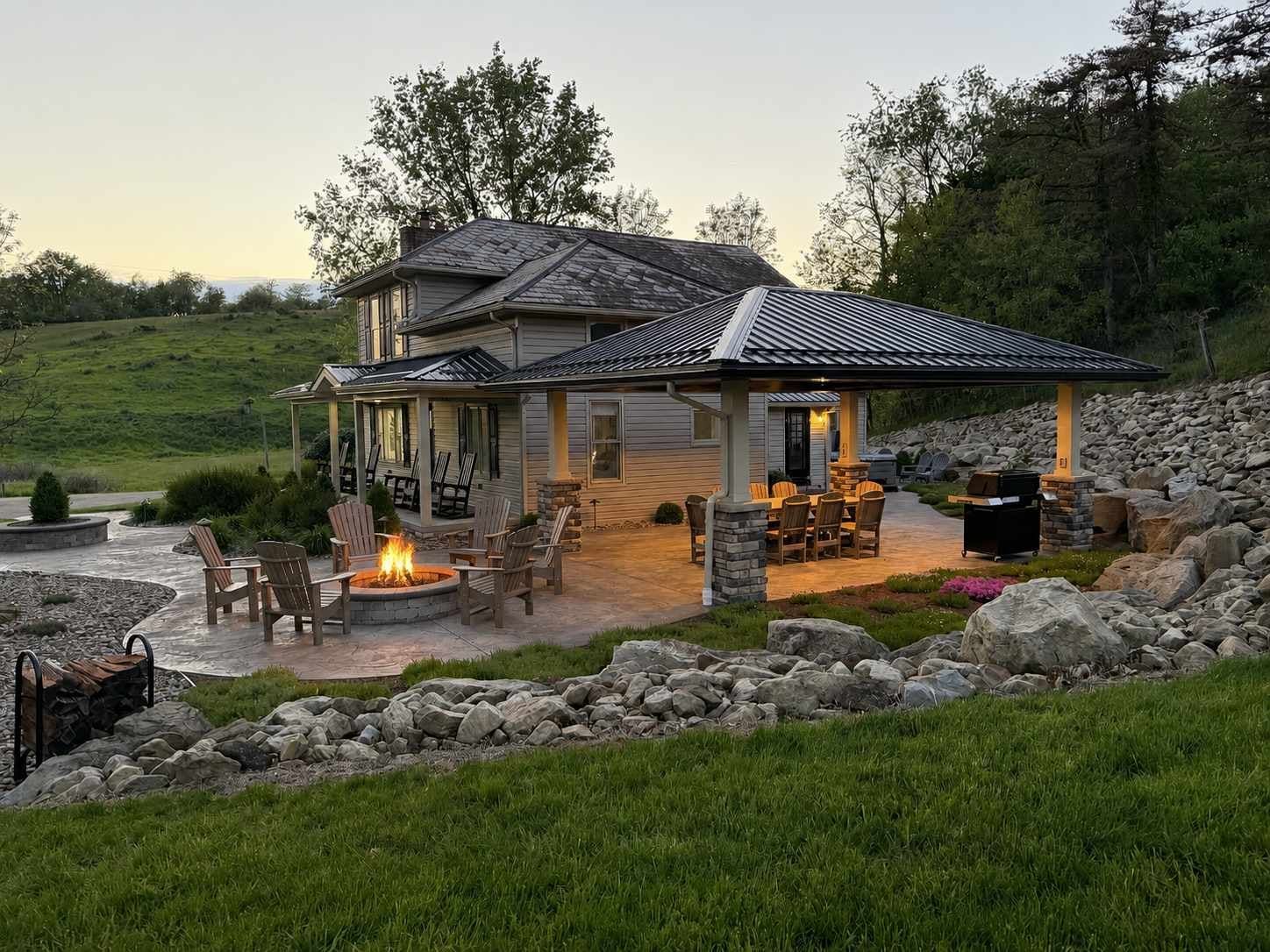 A two-story house with a covered patio area, outdoor seating, and a fire pit.