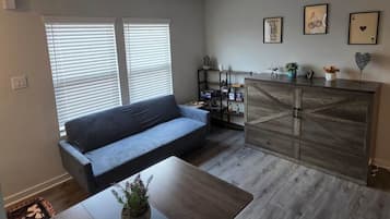 Una sala de estar con sofá, mesa de centro y aparador de madera con objetos decorativos.