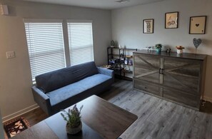 Una sala de estar con sofá, mesa de centro y aparador de madera con objetos decorativos.