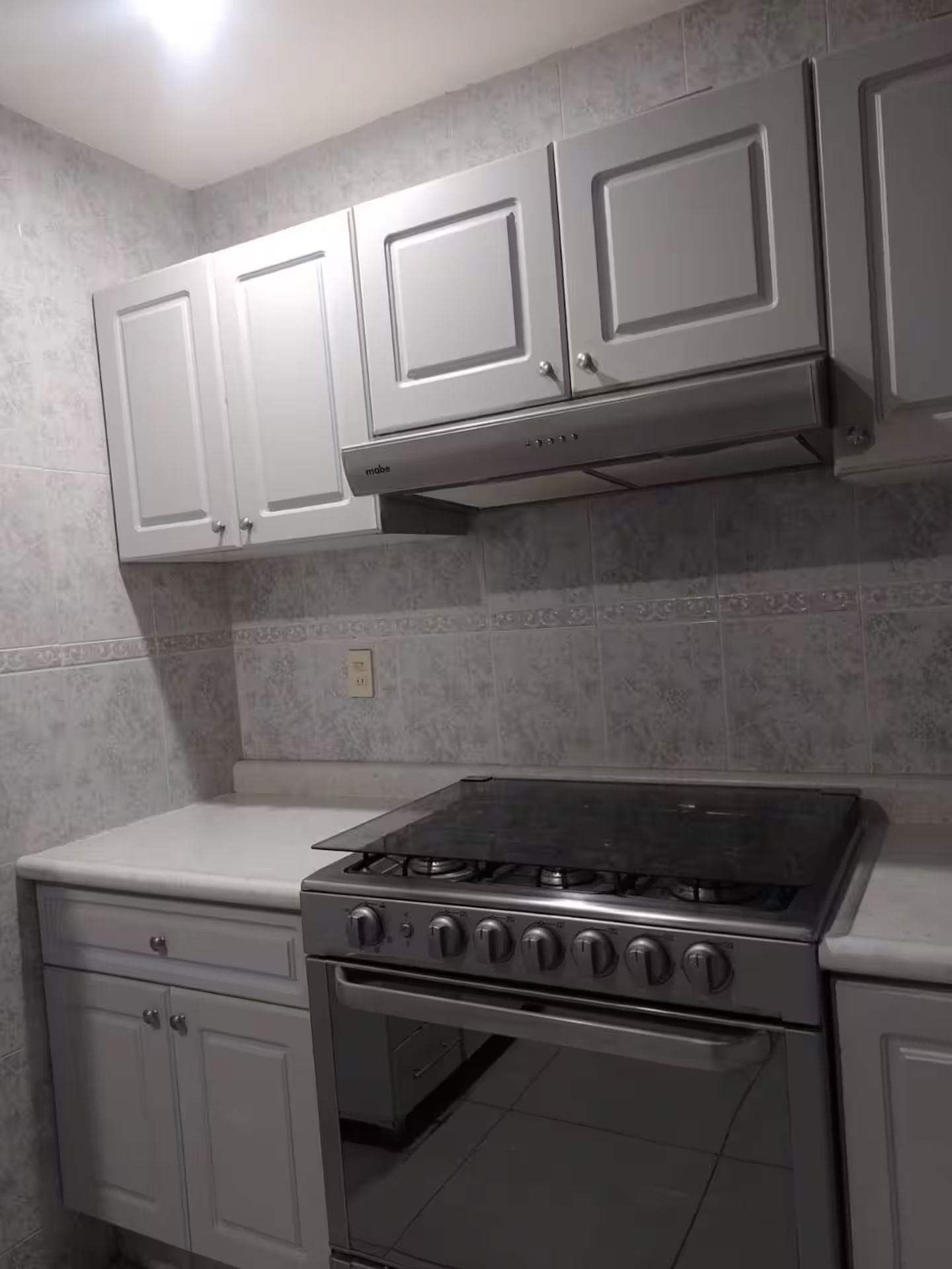 A kitchen with white cabinets, a gas stove, and an oven.