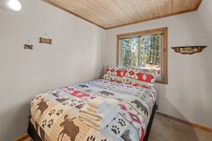 Une chambre à coucher avec un lit, une fenêtre, une étagère fixée au mur et un panneau accroché au mur.