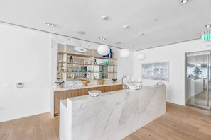 Un espace d’accueil moderne avec un comptoir en marbre, des étagères en bois et des luminaires suspendus.