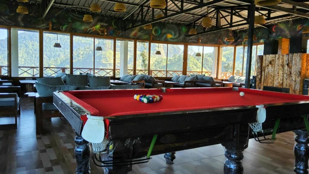 A pool table with balls, surrounded by seating and a view of greenery.