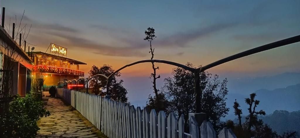A hotel with a neon sign, a stone pathway, and a white picket fence.