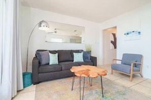 Ein Wohnzimmer mit einer Couch, einem Couchtisch, einem Sessel und einer Stehlampe.