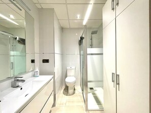 A modern bathroom with a large mirror, a toilet, and a shower area. - Central Granada Apartment for 4 (Granada)