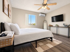 A bedroom with a bed, a ceiling fan, a window, a TV, and a bedside table with a basket. - Modern Tempe 1BR Retreat | Near ASU & Downtown (Tempe)