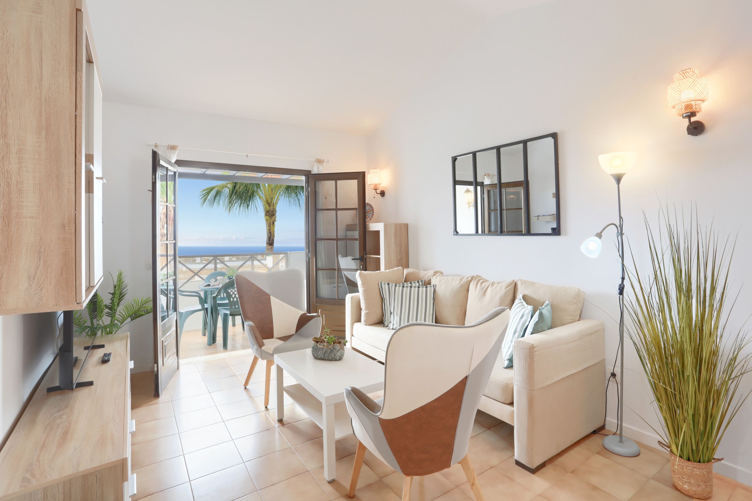 A modern living room with a sofa, chairs, a coffee table, and a view of the sea.