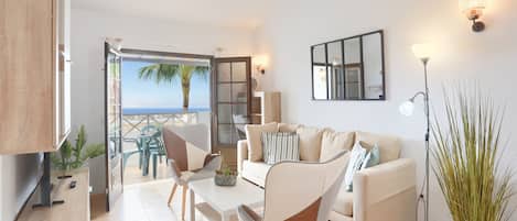 A modern living room with a sofa, chairs, a coffee table, and a view of the sea.