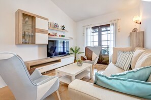 A modern living room with a flat-screen TV, a coffee table, a sofa, and a chair. - Apartamento NATALIA BEACH (Puerto del Carmen)