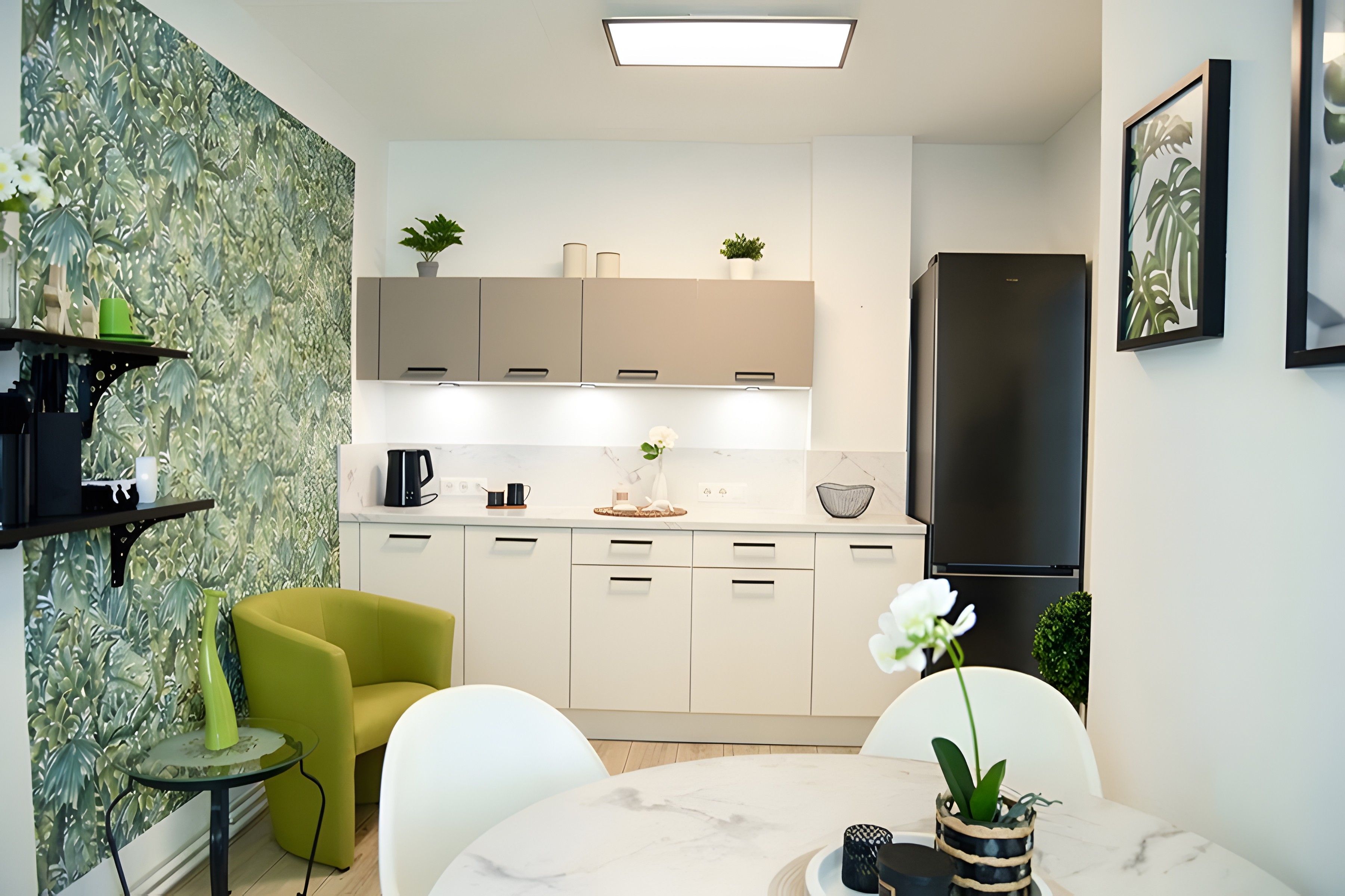 Eine moderne Küche mit weißen Schränken, einem schwarzen Kühlschrank und einem Essbereich mit einem runden Tisch und Stühlen.