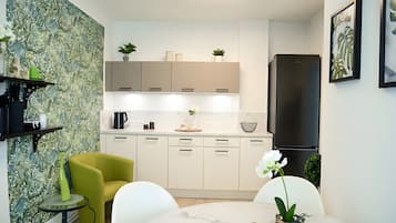 Eine moderne Küche mit weißen Schränken, einem schwarzen Kühlschrank und einem Essbereich mit einem runden Tisch und Stühlen.