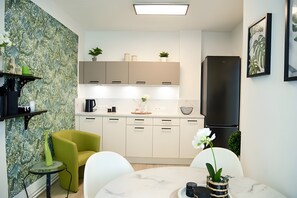 A modern kitchen with white cabinets, a black refrigerator, and a dining area with a round table and chairs.