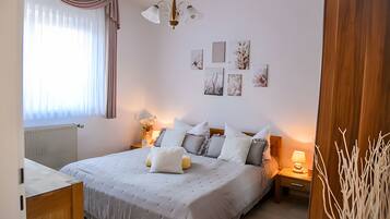 A bedroom with a bed, bedside tables, a lamp, a radiator, and artwork on the wall.