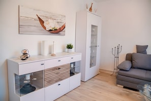 A modern living room with a white cabinet, a grey sofa, and a glass coffee table.